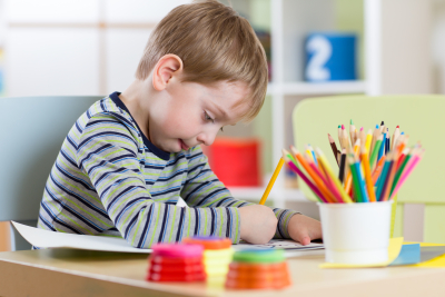 Preschool kid use pencils and paints for his homework